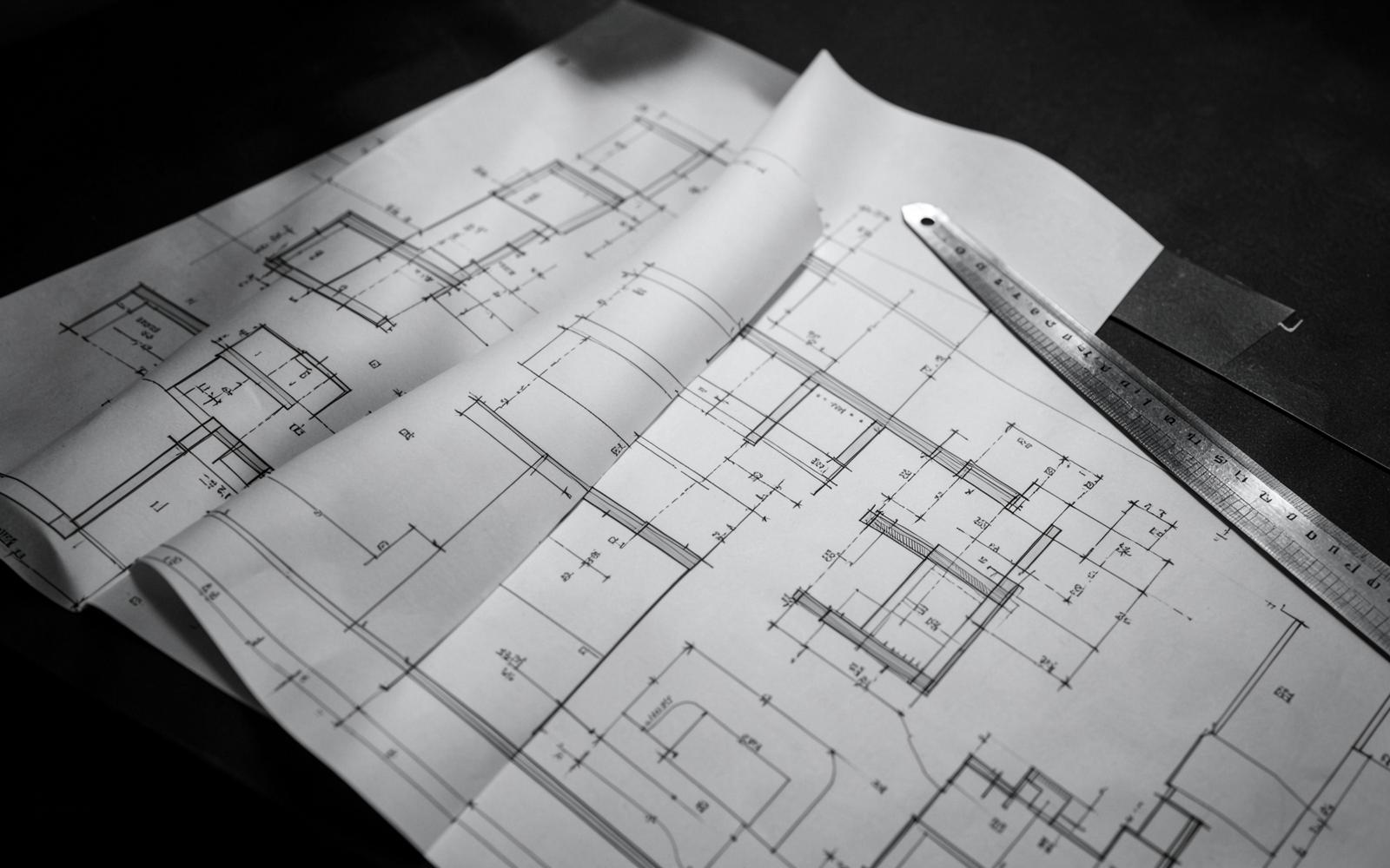 Architectural blueprints and scale drawings spread on a review table